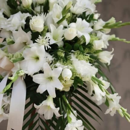 Fotografía macro premium de Pedestal Fúnebre Salvación, con lirios, rosas y gladiolos blancos, follaje verde y rocío sutil. C