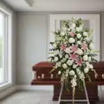Pedestal de homenaje "El Legado de Josafat" con rosas blancas, lirios rosados y gladiolos en sala de velación moderna, simbol
