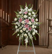 Pedestal floral funerario "El Legado de Josafat" con lirios rosas, rosas blancas y gladiolos en sala de velación elegante.