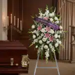 Pedestal floral "El Legado de Josafat" con rosas blancas, lirios rosados y gladiolos, cinta morada "En Profunda Simpatía" jun