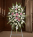 Pedestal floral funerario "El Legado de Josafat" con lirios rosas, rosas blancas y gladiolos en sala de velación elegante.