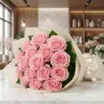 Ramillete o bouquet de rosas rosadas frescas y abiertas, con empaque elegante color crema, sobre superficie de mármol en flor