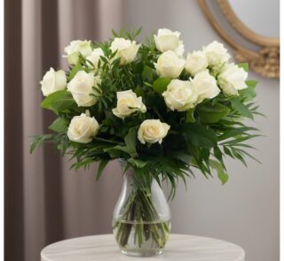 Ramo de 18 rosas blancas frescas en un jarrón de cristal, con follaje verde, sobre una mesa de mármol y fondo elegante.
