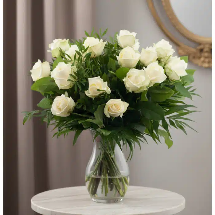Ramo de 18 Rosas Blancas Serena: Pureza y Elegancia Ramo de 18 rosas blancas frescas en un jarrón de cristal, con follaje verde, sobre una mesa de mármol y fondo elegante.